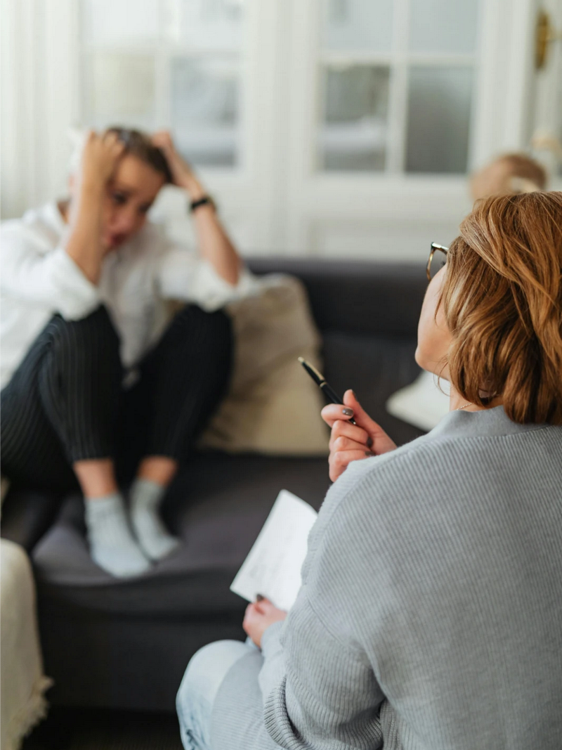 Specialistė su rašikliu ir užrašų knygele rankose aiškina informaciją priešais sėdinčiai merginai.Specialistė su rašikliu ir užrašų knygele rankose aiškina informaciją priešais sėdinčiai merginai.